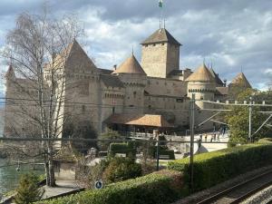 un grand château installé à côté d'une étendue d'eau dans l'établissement Amazing lake view Montreux, à Montreux