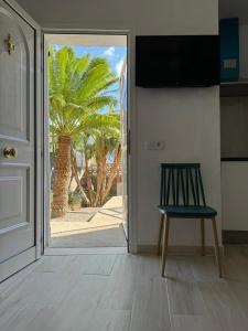 a door to a room with a chair and a palm tree at El Molino in La Aldea de San Nicolas
