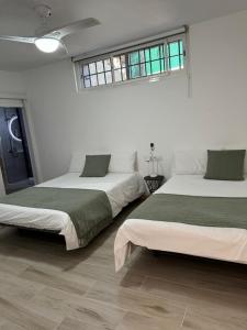 two beds in a room with white walls at El Molino in La Aldea de San Nicolas