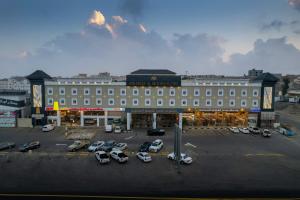 un grand bâtiment avec des voitures garées dans un parking dans l'établissement Msharef almoden hotel فندق مشارف المدن, à Abha