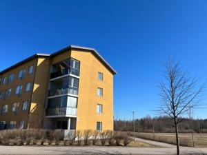 a yellow apartment building with a tree in front of it at 3h + k Golfkentän vieressä in Vantaa