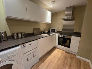 a kitchen with white cabinets and a dishwasher at King’s Cross & Camden : Stylish Flat in London