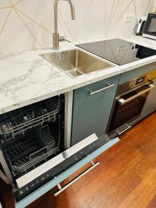 a kitchen with a sink and an open dishwasher at FeWo BEE61 * Langen EXKLUSIV für 4 Personen *Vollausstattung mit Küche* inklusive TERRASSE in Langen