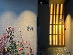 una puerta a un edificio con una planta y flores en TokiToki 時時, en Kioto