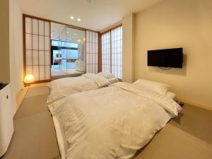 Un dormitorio con una cama grande y un televisor de pantalla plana. en TokiToki 時時, en Kioto