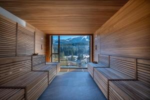 a sauna with wooden benches and a large window at DAMIAN JASNA HOTEL RESORT and RESIDENCES in Demanovska Dolina