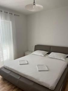 Una cama blanca con dos libros en un dormitorio en Apartment Davor, en Gradac