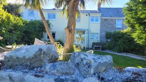 a house with a palm tree and some rocks at Cosy terraced Cornish cottage near the sea in Penzance