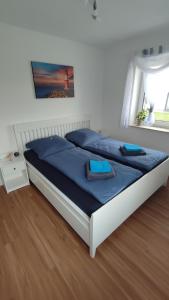 a bedroom with a bed with blue sheets and a window at FeWo "Leuchtturmliebe" 