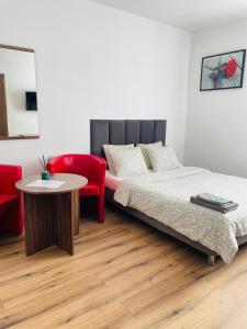 1 dormitorio con cama, mesa y silla roja en Pokoje Gościnne Strumykowa en Lublin