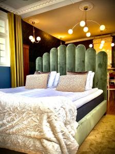 a bedroom with a large bed with a green headboard at Grenna Hotell in Gränna