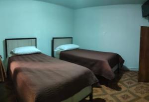 2 camas en una habitación con una pared azul en HOTEL MARISOL, en Iquique