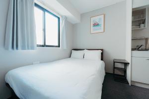 um quarto com uma cama branca e uma janela em unito SHIODOME em Tóquio