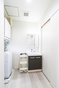 - une cuisine blanche avec un évier et un miroir dans l'établissement Chura Minpaku Ishigaki, à Ishigaki