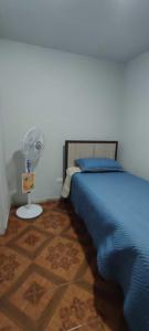 1 dormitorio con 1 cama azul y ventilador en HOTEL MARISOL, en Iquique