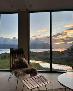 a chair in front of a room with a large window at Designhytte med jacuzzi sentralt i Lofoten in Kleppstad