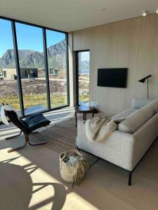 a living room with a couch and a chair at Designhytte med jacuzzi sentralt i Lofoten in Kleppstad