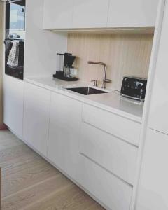 a kitchen with white cabinets and a sink at Designhytte med jacuzzi sentralt i Lofoten in Kleppstad