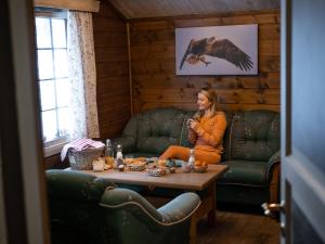 a woman sitting on a couch in a room with a table at Sjodalen Hyttetun og Camping in Stuttgongfossen