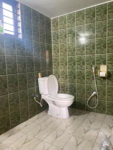a bathroom with a toilet and a green tiled wall at Holiday Home in Khastobir Sylhet Town in Sylhet
