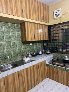 cocina con armarios de madera, fregadero y fogones en Holiday Home in Khastobir Sylhet Town, en Sylhet