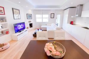 a living room with white furniture and a tv at Anna & Thomas - Sitges Center Apt in Sitges