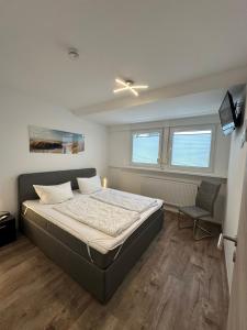 ein Schlafzimmer mit einem Bett und einem Stuhl darin in der Unterkunft Ferienwohnungen Haus Boje in Neuharlingersiel