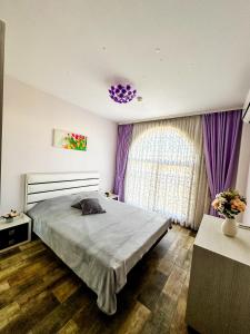 a bedroom with a bed and a window with purple curtains at Апартамент Каскадас В54 in Sunny Beach