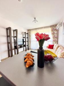 a living room with a table with a vase of flowers at Апартамент Каскадас В54 in Sunny Beach