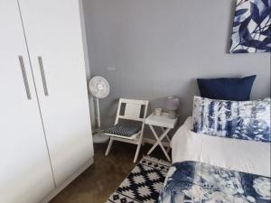 a small bedroom with a bed and a chair at Karoo Nest - Calitzdorp in Calitzdorp