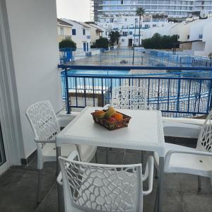 a table and chairs with a bowl of fruit on a balcony at G&E Harbour Apartments in Lachi