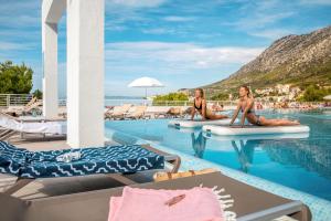 two women sitting on surfboards in the pool at a resort at TUI BLUE Adriatic Beach - All Inclusive - Adults Only in Igrane