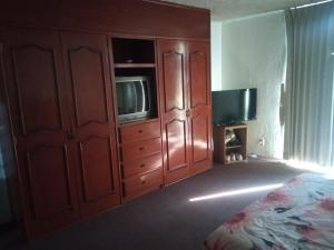 Schlafzimmer mit einem Bett und einem Schrank mit einem TV in der Unterkunft El paraíso in Guadalajara