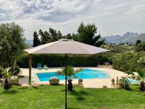 una sombrilla en el césped junto a una piscina en Villa Flore - Penthouse - apartment in villa, en Casteldaccia