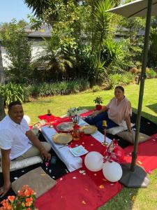 two people sitting at a picnic table on a blanket at Africa Paradise - OR Tambo Airport Boutique Hotel in Benoni