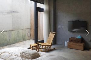 a bedroom with a bed and a chair and a tv at 土造粗樓 包棟依照人數分配房間 in Hengchun South Gate