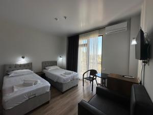 una camera d'albergo con due letti e una televisione di Majestic a Kobuleti