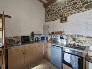 a kitchen with wooden cabinets and a stone wall at Immaculate 1-Bed Cottage in Bideford in Bideford