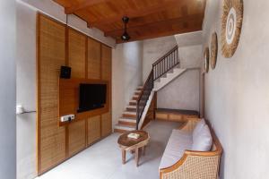ein Wohnzimmer mit einem Sofa, einem TV und einer Treppe in der Unterkunft Ikada Villa by Pramana Villas in Ubud