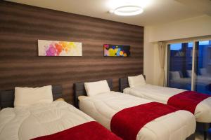 a bedroom with three beds with red and white blankets at AMS海宝楼403 in Otaru