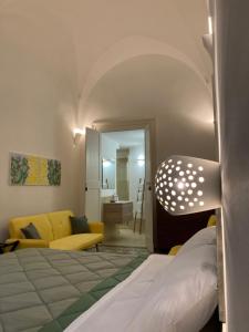ein Schlafzimmer mit einem Bett und ein Wohnzimmer mit einem gelben Sofa in der Unterkunft B&B Antica Dimora dell'Angelo in Nardò