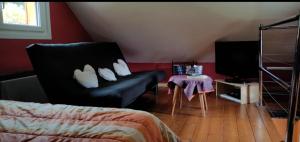 a bedroom with a couch and a tv and a table at Chalet pour amoureux de la nature avec vue sur le lac de Retournemer in Xonrupt-Longemer