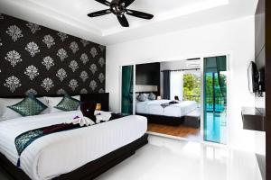a bedroom with two beds and a ceiling fan at Phutara Lanta Resort - SHA Extra Plus Koh Lanta in Ko Lanta