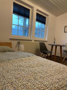 a bedroom with a bed and a table and two windows at Landhaus am Loh in Wesel