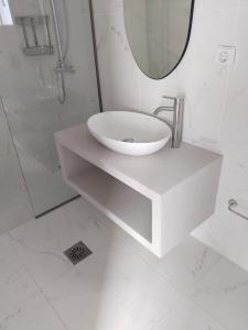 uma casa de banho branca com um lavatório e um espelho em MENTOROS VILLAS em Karavádhos