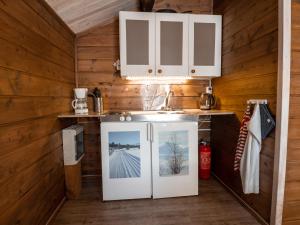 a kitchen with wooden walls and a refrigerator with a picture at Sjodalen Hyttetun og Camping in Stuttgongfossen