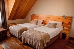 2 camas en una habitación de hotel con techos de madera en Głęboczek Vine Resort& Spa en Wielki Głęboczek