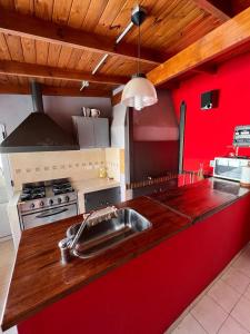 eine Küche mit einem Waschbecken und einer roten Wand in der Unterkunft Casa para 7 personas pileta in Monte Hermoso