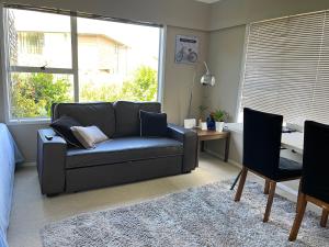 a living room with a couch and a desk at Family suite at Campbells Bay -Netflix TV in Auckland