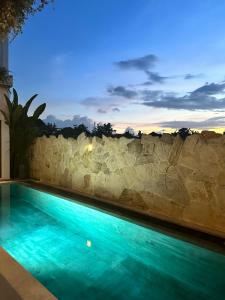 a swimming pool in front of a stone wall at Three Palms Surf & Stay Medewi in Airsatang +30 photos
